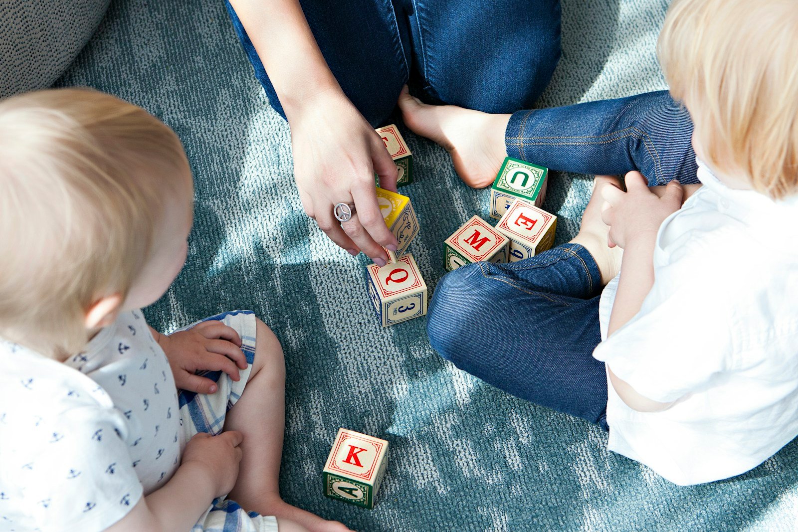 Child playing with alphabet blocks on a rug