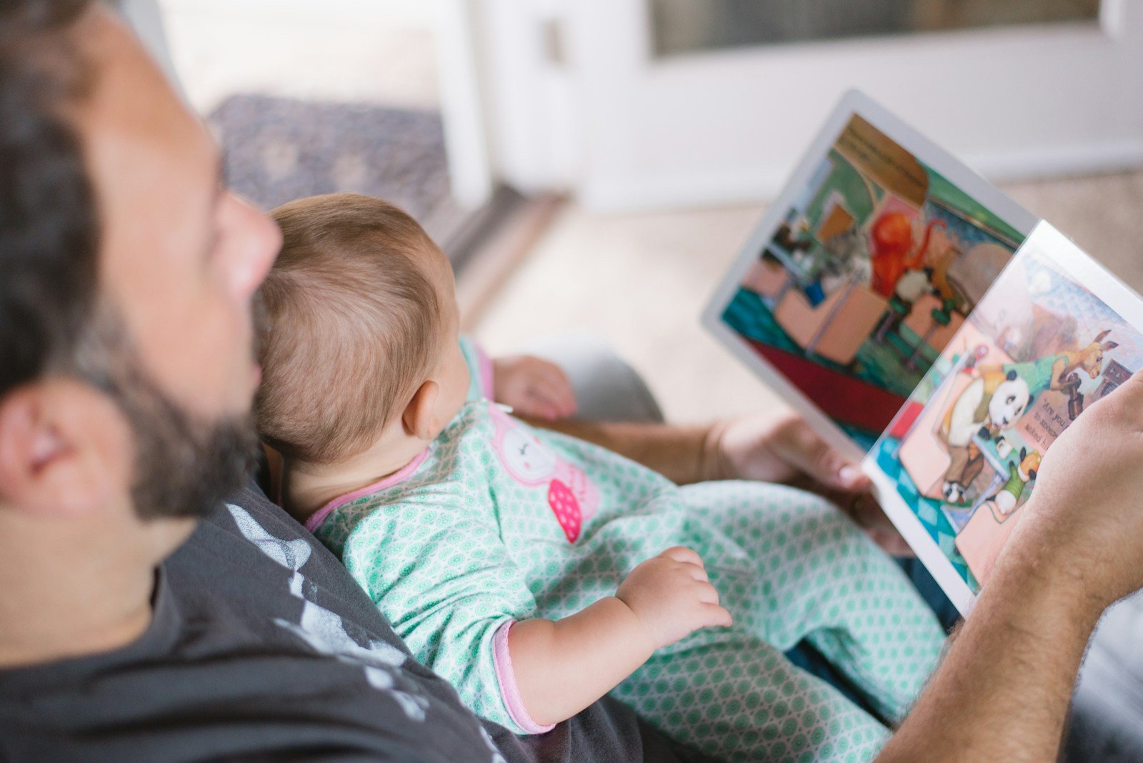 Baby looking at a colorful picture book with an adult