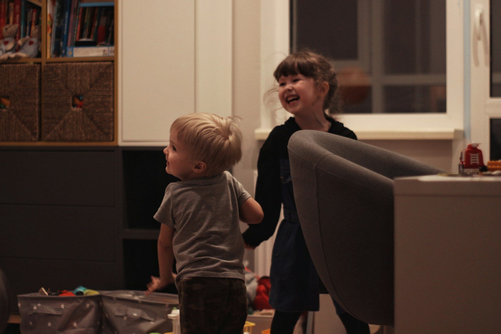 Two young children laughing and playing in a living room